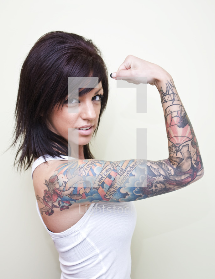 Woman with tattoos on her arm flexing her muscle.