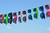 sunglasses hanging on a wire against a blue sky 