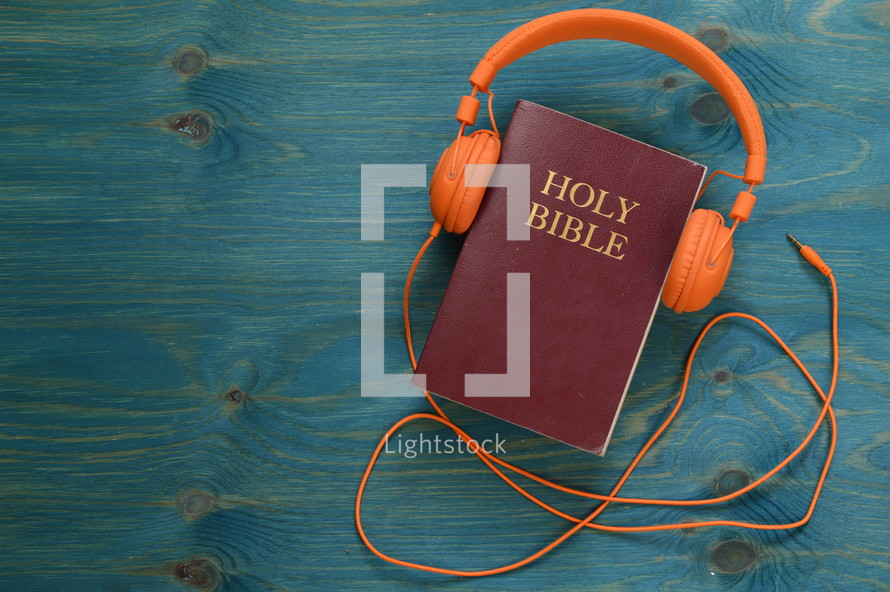 bible with orange headphones on teal wooden background