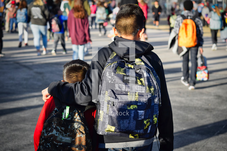 protective big brother walking little brother home from school 