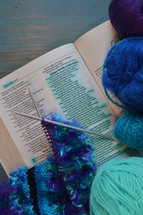 wool and a piece of knitting on a bible open at the page of Proverbs 31: The Wife of Noble Character with the line: She selects wool and flax marked 