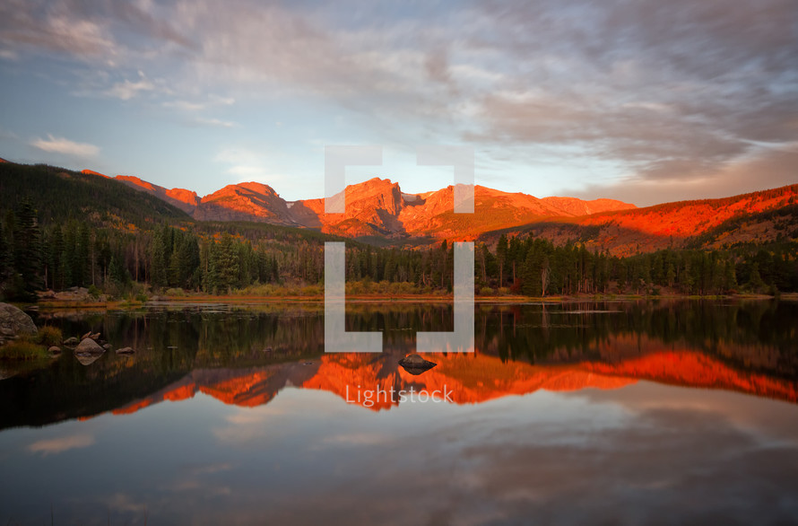 reflection of red rock mountains and sky in lake water 