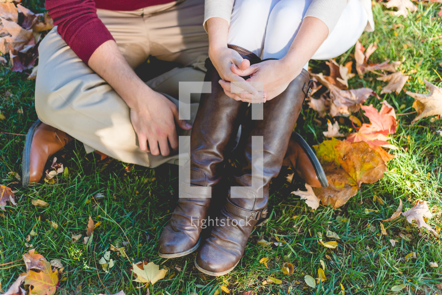 legs of a couple sitting in grass