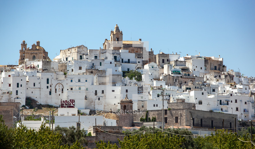 panoramic view of the white and old city of Ostuni on a hilltop and with the cathedral on top.