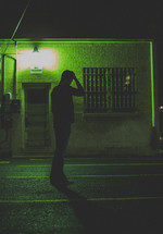 man standing in a dark alley with his hand on his head