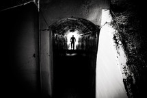 silhouette of a man walking in a tunnel 