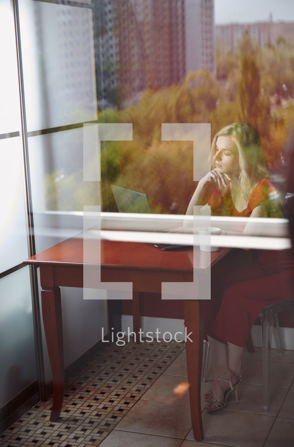 view through a window of a businesswoman working at her desk 