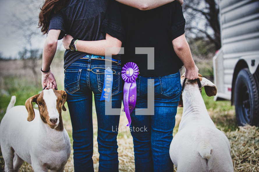 After months of hard work and learning about responsibility, sisters embrace after showing their goats in a county fair.