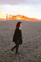 a woman walking on a beach in sneakers 