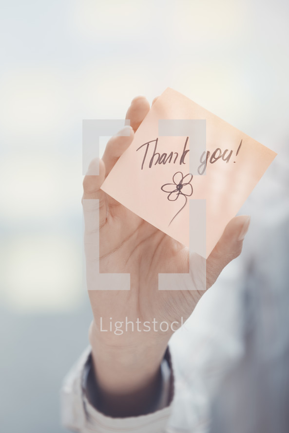 a woman holding a sticky note with the words thank you 