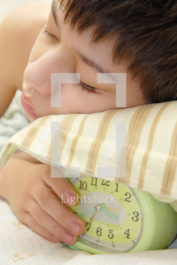 sleeping kid next to an alarm clock 