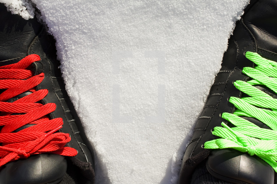 red and green shoe laces on black sneakers standing in snow
