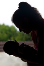 silhouette of a mother holding a swaddled newborn 