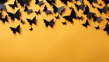 Black paper bats flying on orange background. Halloween concept.