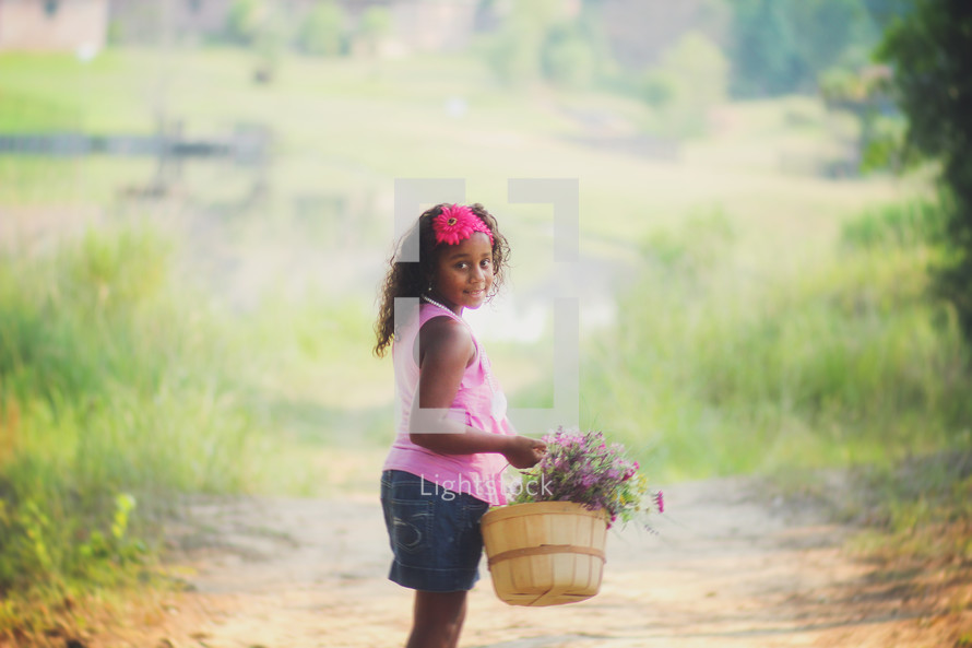 a girl carrying a basket of flowers 