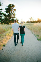 couple walking down a gravel road holding hands 