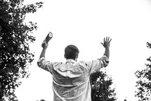 a man holding a Bible with hands raised 