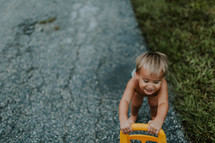 a toddler in a diaper pushing a toy outdoors 