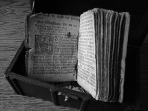 Ancient prayer book from Martin Luther, in a treasure chest on a wood floor.