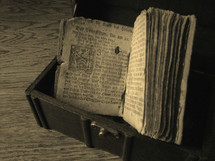 Ancient prayer book from Martin Luther in a treasure chest on a wood floor.
