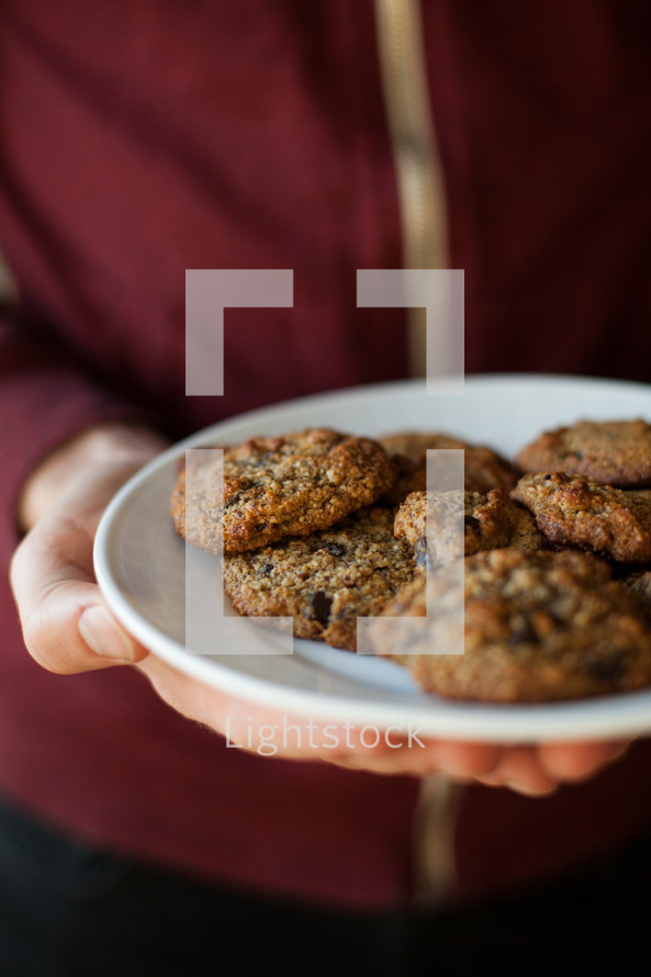 a woman holding a plate of cookies 