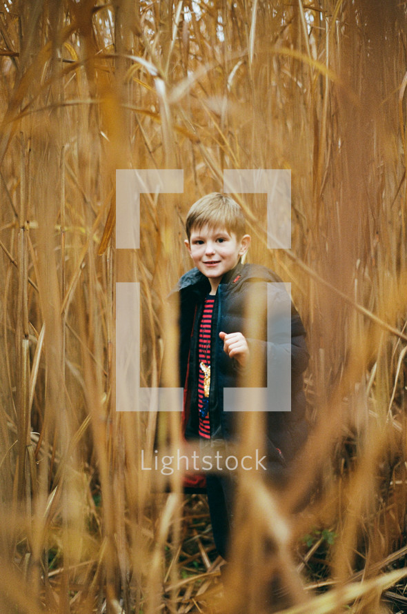 a boy hiding in a field of tall grass 