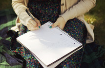 woman writing in a journal outdoors 