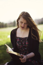 woman reading from a Bible outdoors 