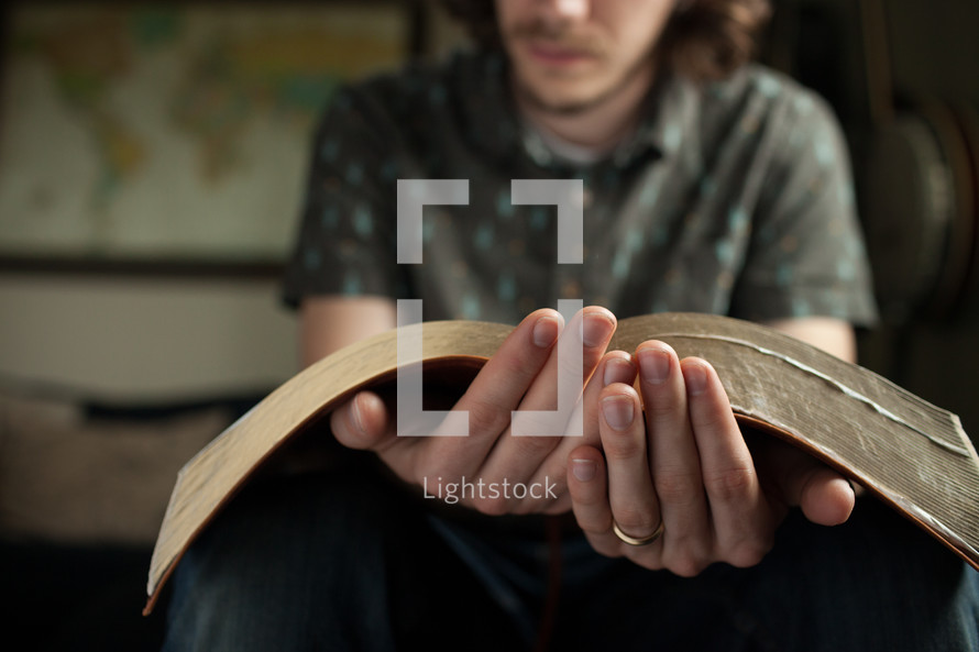 a man sitting reading an oversized Bible 