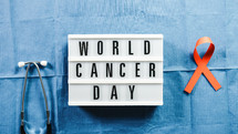world cancer awareness day signboard and orange ribbon