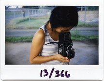polaroid picture of a woman looking into a vintage camera 