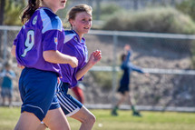 girls running on a soccer field 