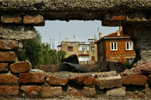 view of a village through a hole in a brick wall 