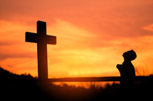 silhouette of a boy praying at sunset 