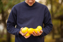 a man holding and looking down at lemons 