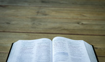 an open Bible on a wood table 
