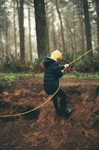 a child using a rope to get out of a ditch 