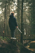 a boy with a sword in a forest 