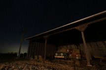 Barn with vintage trucks at night