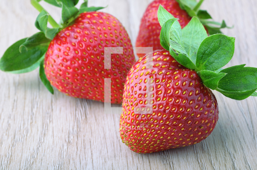 three ripe strawberries on the table closeup