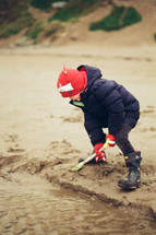 a boy shoveling sand 