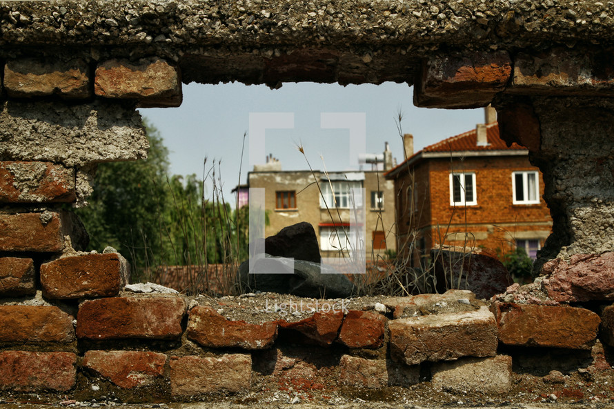 view of a village through a hole in a brick wall 