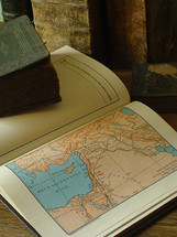 Old books and an old Bible with a map of Israel.
