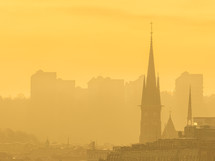 The foggy morning sky reveals Gothenburgs skyline of sprawling cityscape, its built structures and grand church towers emerging from the haze.