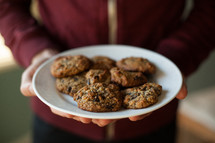 a woman holding a plate of cookies 