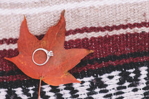 engagement ring on a fall leaf on a blanket 