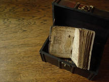 Ancient prayer book from Martin Luther in a treasure chest on a wood floor.