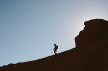 silhouette of a man hiking down a mountain 
