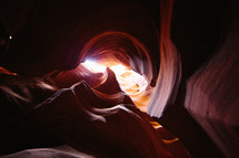 sunlight shining into a red rock cave 