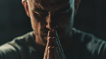 A man praying with his hands near his face